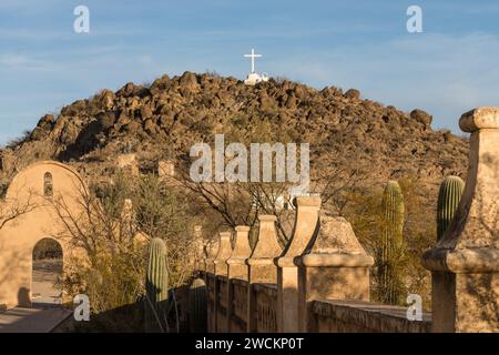 Porta ad arco attraverso il muro di protezione intorno alla missione San Xavier del Bac, Tucson, Arizona. Dietro c'è la collina della Grotta con la sua croce bianca. Foto Stock