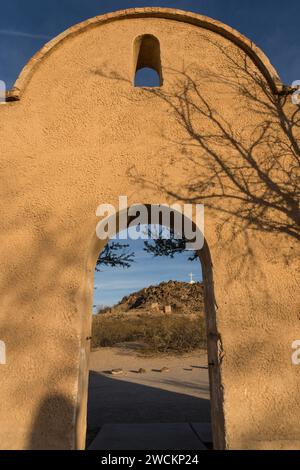 Porta ad arco attraverso il muro di protezione intorno alla missione San Xavier del Bac incornicia la Grotto Hill, Tucson Arizona. Foto Stock