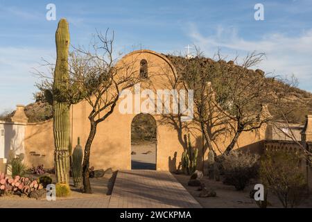 Porta ad arco attraverso il muro di protezione intorno alla missione San Xavier del Bac, Tucson, Arizona. Dietro c'è la collina della Grotta con la sua croce bianca. Foto Stock