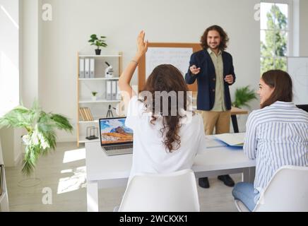 Studentessa che solleva la mano durante la lezione in aula Foto Stock