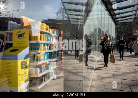 Lavoratori cittadini e acquirenti in un paesaggio urbano di riflessi simmetrici e diagonali al dettaglio fuori di una filiale di Boots the Chemist nella City di Londra, il quartiere finanziario della capitale, il 16 gennaio 2024, a Londra, Inghilterra. Foto Stock