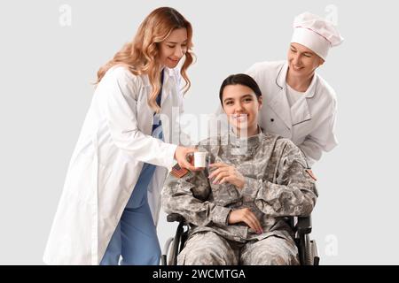 Donne di diverse professioni che aiutano donne soldato in sedia a rotelle su sfondo grigio Foto Stock