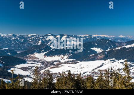 Liptovska Luzna villaggio con colline di Velka Fatra e Mala Fatra montagne in Slovacchia durante l'inverno - viiew bellow Sedlo pod Skalkou a Nizke Tatry m Foto Stock