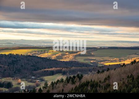 Paesaggio presso il Grosser Zacken, regione vulcanica del Taunus. Una giornata d'autunno nuvolosa e soleggiata, prati, colline, campi e foreste con vista del tramonto. Foto Stock