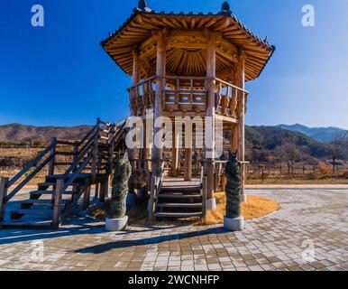 Due statue in bronzo di draghi in piedi di fronte a un gazebo in legno a due piani in un parco pubblico situato vicino a Geumsan, Corea del Sud Foto Stock