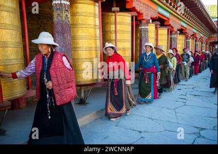 Tibet, Kham, Litang. Nomadi tibetani vicino a Litang. Gente che circonda il monastero con le ruote di preghiera. Foto Stock