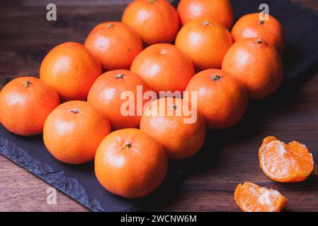 clementine fruit. Foto dei mandarini allineati in file sul tabellone di pietra nera. Foto Stock