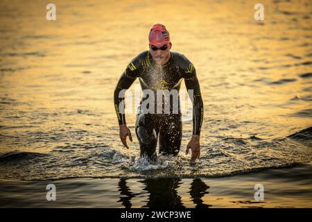 Primo posto triatleta che esce dall'acqua in una muta che soffia durante una bella alba per passare al settore ciclistico a Gandia, Valencia, Spagna Foto Stock