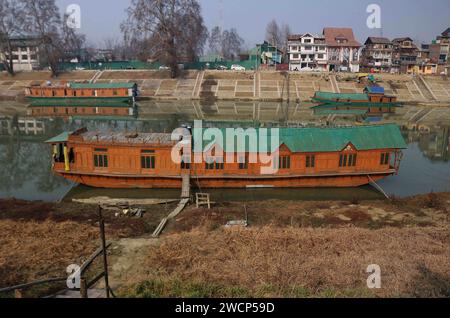 Srinagar Kashmir, India. 15 gennaio 2024. Le case galleggianti sono viste sulle rive del fiume Jhelum a Srinagar. Un lungo periodo invernale secco lascia il fiume Jhelum a Historic Low, mettendo a rischio le case galleggianti e deludenti sciatori a Gulmarg. Il 15 gennaio 2024, Srinagar Kashmir, India. (Immagine di credito: © Firdous Nazir/eyepix via ZUMA Press Wire) SOLO USO EDITORIALE! Non per USO commerciale! Foto Stock