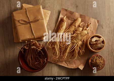 Dang shen all'interno di una ciotola, il Ginseng posto su una carta disposta con altre erbe tradizionali e diverse confezioni di medicinali. Le erbe aiutano il corpo a ottenere più e Foto Stock