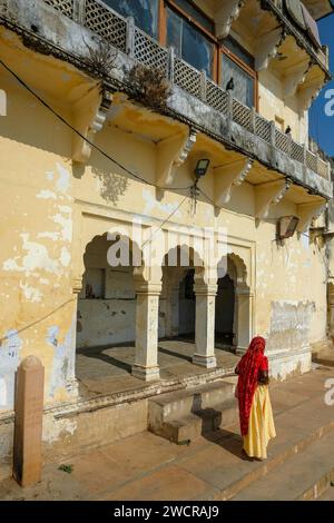 Pushkar, India - 4 gennaio 2024: Una donna che cammina lungo un ghat del lago Pushkar nel Rajasthan, India. Foto Stock