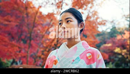 Donna nel parco, asiatica e pacifica, pensa alla vita con riflessi e tranquillità in abiti tradizionali. Viaggio, giardino giapponese e natura per Foto Stock