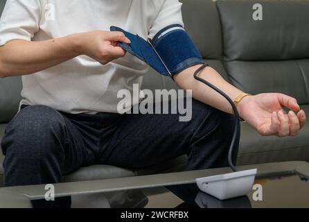 Uomo di mezza età che usa il misuratore della pressione sanguigna Foto Stock