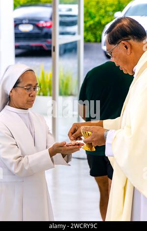 Sacerdote che dona comunione alla Chiesa cattolica Maria Ausiliatrice, Ko Samui, Chaweng, Thailandia Foto Stock