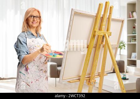 Donna con un grembiule dipinto su una tela a casa Foto Stock