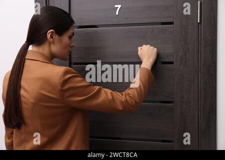 Donna in giacca che bussa alla porta all'interno Foto Stock