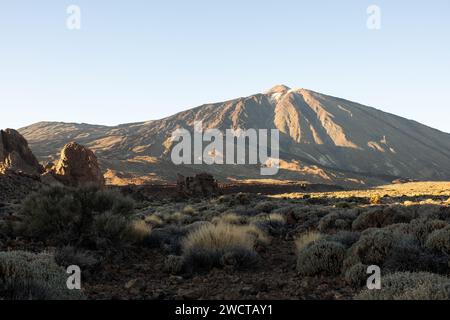 La luce del sole dorata bagna un maestoso picco di montagna e un terreno accidentato in una tranquilla foto di paesaggio Foto Stock