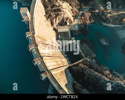 Vista dall'alto spettacolare prospettiva aerea di una diga che proietta lunghe ombre sull'acqua all'alba o al tramonto Foto Stock