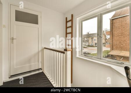 una stanza vuota con una finestra e un po' di rifiniture bianche sul davanzale si trova di fronte alla porta Foto Stock