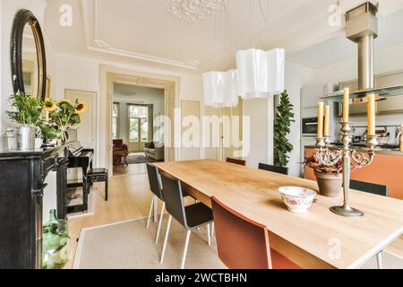 Una spaziosa sala da pranzo con arredi classici e un grande tavolo in legno sotto eleganti luci a sospensione. Foto Stock