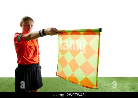 Concentrati sulla bandiera. Giovane donna, assistente arbitro che alza bandiera significa posizione fuorigioco sullo sfondo bianco dello studio Foto Stock