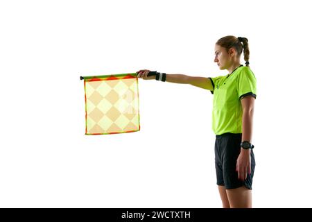 Assistente arbitro, giovane donna in uniforme in piedi sul campo e alzando bandiera significa posizione fuorigioco su sfondo bianco studio Foto Stock