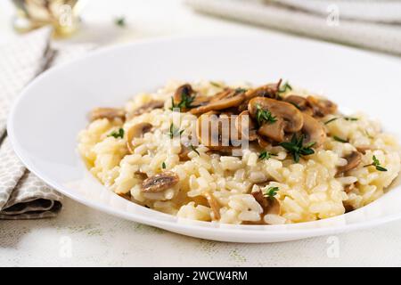 Piatto con delizioso risotto con funghi in piatto. Porridge di riso con fungo e tmyne. Piatti caldi, cucina italiana. Foto Stock
