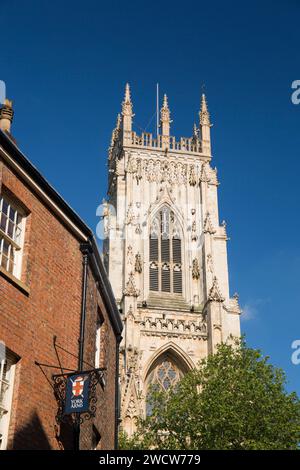 York, North Yorkshire, Inghilterra. Vista dall'angolo basso della torre sudoccidentale del XV secolo della York Minster, insegna del pub in primo piano. Foto Stock