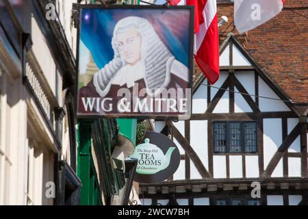 Lincoln, Lincolnshire, Inghilterra. Cartelli appesi sopra una tradizionale sala da tè e una casa pubblica sulla ripida collina, Leigh-Pemberton House del XVI secolo oltre. Foto Stock