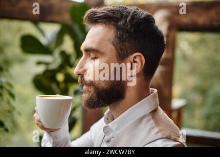 concentrato e affascinante leader aziendale con barba dallo stile elegante e bevendo il suo caffè Foto Stock