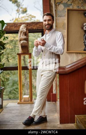 allegro e attraente capo d'affari con la barba e l'elegante stile elegante che beve il suo caffè Foto Stock