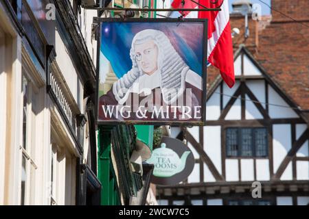 Lincoln, Lincolnshire, Inghilterra. Cartelli appesi sopra una tradizionale casa pubblica e sala da tè sulla ripida collina, Leigh-Pemberton House del XVI secolo oltre. Foto Stock