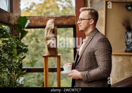 leader aziendale sofisticato e mirato con occhiali in elegante abito che beve il suo caffè caldo Foto Stock