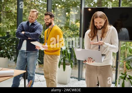 concentrati su un uomo gioioso con un abbigliamento casual e videoclip e sui suoi colleghi sfocati che parlano di startup Foto Stock