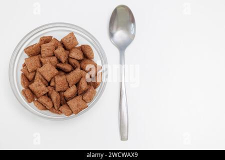 Coppette di mais croccanti dolci in un recipiente di vetro con cucchiaio in metallo su sfondo bianco con spazio coperto Foto Stock