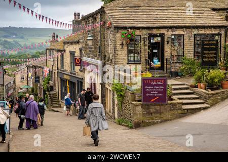 Regno Unito, Inghilterra, Yorkshire, Worth Valley, Haworth, Main Street, visitatori su una collina acciottolata Foto Stock