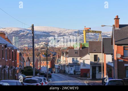 Belfast, Irlanda del Nord, Regno Unito. 17 gennaio 2024. Clima britannico - sole invernale brillante dopo il brutto gelo e il ghiaccio di ieri sera, neve sulle colline di Belfast su Divis e Black Mountain, vista attraverso la Belfast industriale dal lato orientale della città. Credito: CAZIMB/Alamy Live News. Foto Stock