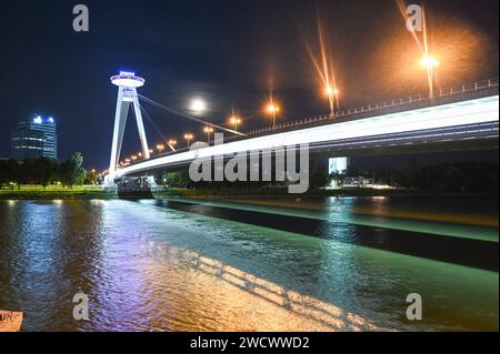 Slovacchia, Bratislava, la pista ciclabile Eurovelo 6, il ponte e la torre Vyhliadkova veza UFO con illuminazione notturna e il Danubio Foto Stock
