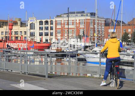 Francia, Nord, Dunkirk, Bassin du Commerce, ciclista di fronte al porticciolo con il battello leggero Sandettié (1947) parte della collezione di filoni del Dunkirk Port Museum Foto Stock