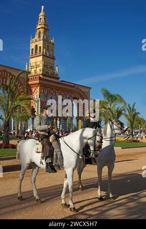 Spagna, Andalusia, Cordova, cavalieri in costume tradizionale a cavallo di fronte alla monumentale porta d'ingresso gialla e rossa della feria de Nuestra señora de la salud Foto Stock