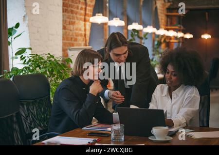 Processo collaborativo di studenti multiculturali, femminili e maschili, qualificati durante il brainstorming in biblioteca. Concetto di lavoro e studio. Foto Stock