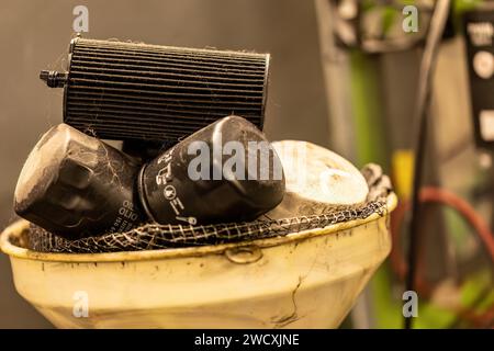 Foto dei vecchi filtri dell'olio esausti in un'officina, che simboleggiano lo smaltimento dei rifiuti pericolosi nella manutenzione automobilistica. Foto Stock