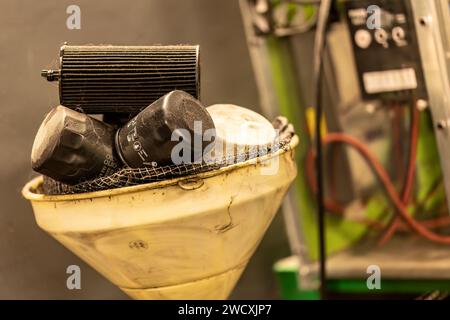 Foto dei vecchi filtri dell'olio esausti in un'officina, che simboleggiano lo smaltimento dei rifiuti pericolosi nella manutenzione automobilistica. Foto Stock