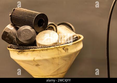 Foto dei vecchi filtri dell'olio esausti in un'officina, che simboleggiano lo smaltimento dei rifiuti pericolosi nella manutenzione automobilistica. Foto Stock