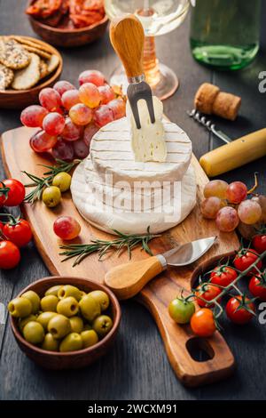 Piatto di formaggi con brie, Camembert, uva, olive e pomodori Foto Stock