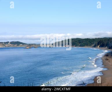 Port Orford Bay, in Oregon, ha numerosi picchi di mare e isole al largo. L'acqua e il cielo sono blu. Foto Stock