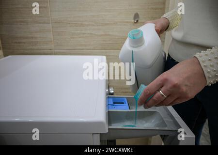 una donna versa il detergente nella lavatrice. Foto Stock