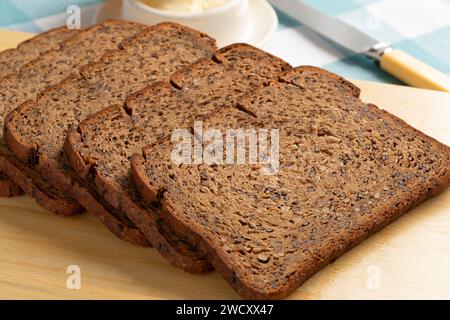 Sottili fette di pane di lino fresco cotto in primo piano su un tagliere Foto Stock