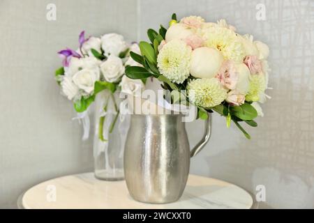 Splendidi mazzi di nozze in brocche d'acqua sul tavolo interno Foto Stock