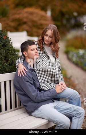 Romanticismo autunnale: Giovani coppie che si abbracciano e si baciano sulla panchina del parco. Giovani coppie che si baciano e si rallegrano al lago. adorabili giovani coppie che si baciano all'aperto Foto Stock